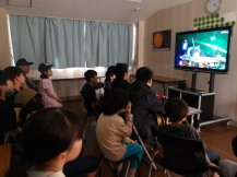 小学生と中学生がテレビゲームで一緒に遊んでいる様子の写真