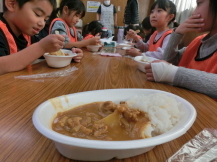 集会室に集まりカレーを食べる子どもたちの写真