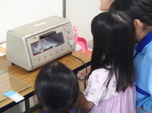 女の子が中学生と一緒にプラバンが焼けるのを見ている写真