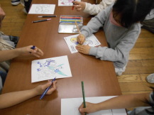 子どもたちがカードケースの絵柄に色を塗っている写真