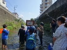 紙芝居で川に関する講義をする講師とそれを聞く子どもたちの写真