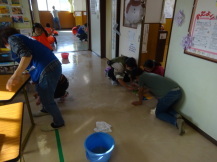館内を清掃する子どもたちと地域住民の写真