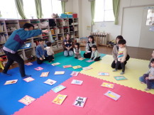 乳幼児室でキャラクターの描かれたカードで絵合わせをして遊ぶ乳幼児親子の写真