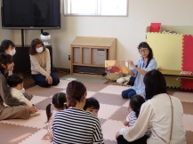 ボランティアの方による読み聞かせを聞いている乳幼児親子の様子の写真