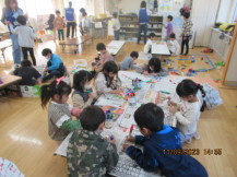 テーブルについて、紙パックに絵を描く児童たち
