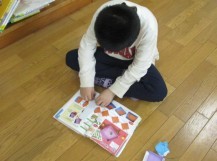 おりがみの本を見ながら一人で折り紙を折っている子どもの写真