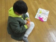 折紙の本を見ながら折り紙を折っている子どもの写真