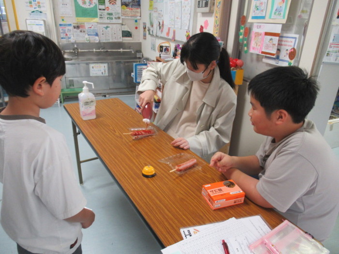 中学生がフランクフルトの販売をお手伝いしている様子