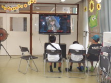 テレビ画面で流れる映画を真剣に見ている小学生児童の写真