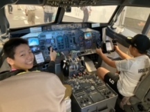 飛行機のコックピッドを体験する小学生児童の写真