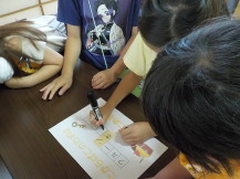 子どもがクイズの答えを書いている写真