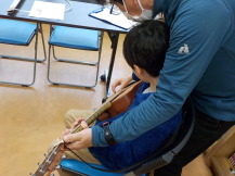 子どもがギターの弾き方を教わっている写真