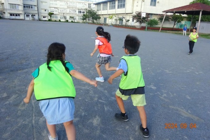 校庭で鬼ごっこをするこどもたちの写真